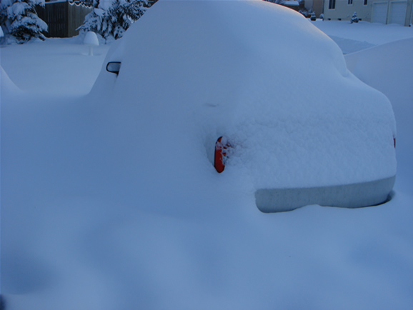 A car almost completely covered with snow.